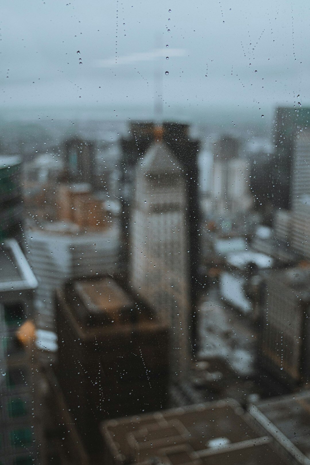 Ventana con gotas de lluvia y luces de la ciudad desenfocadas de fondo